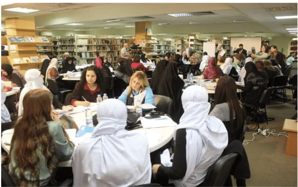 Group of people sitting at round tables writing and working